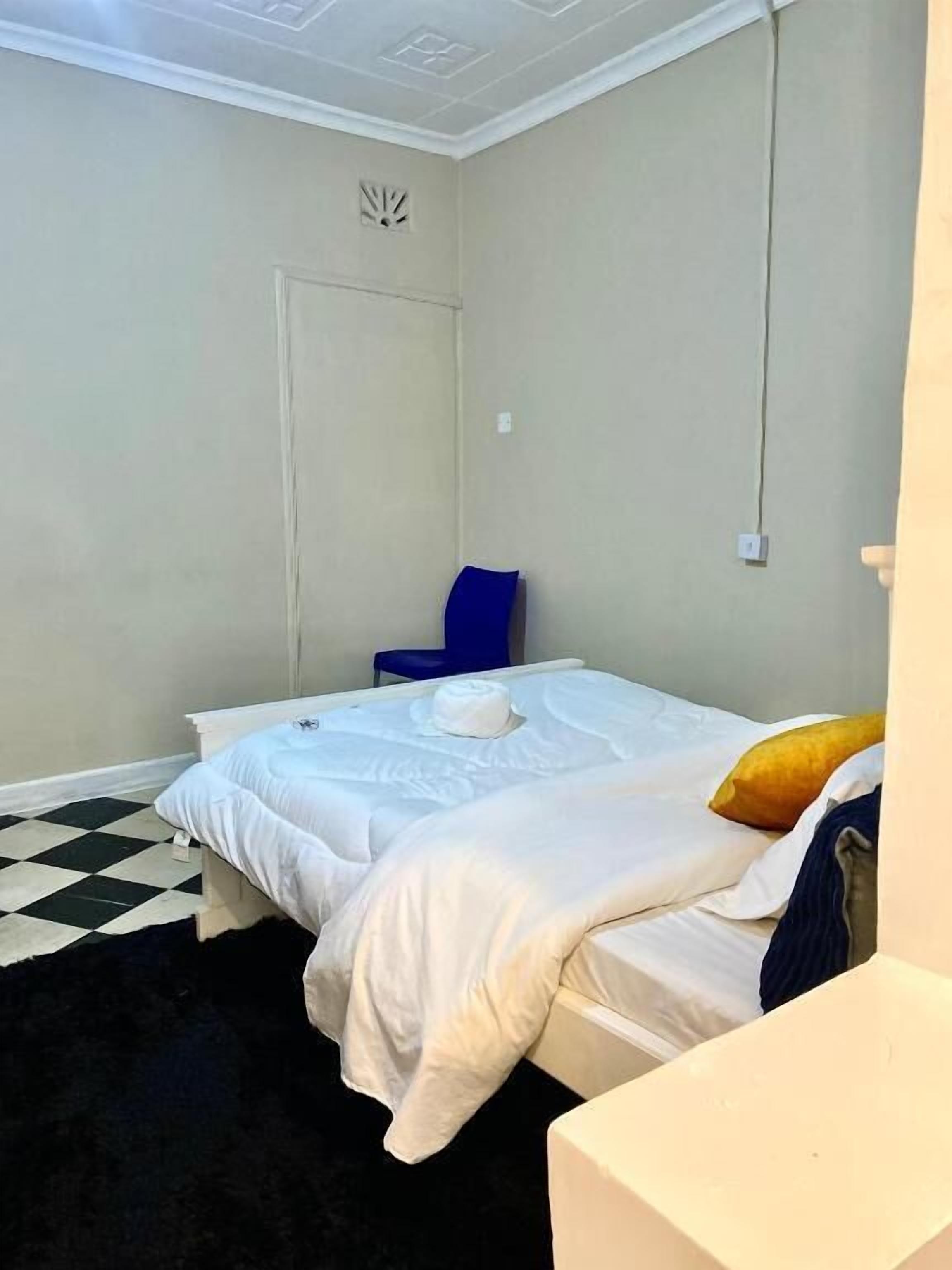 A bedroom with a bed, a chair, and a small table.