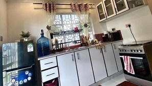 Une cuisine de taille réduite, équipée d’un réfrigérateur, d’une cuisinière et de placards.
