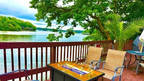 Une terrasse extérieure avec une table et des chaises à plateau en verre, donnant sur un lac.