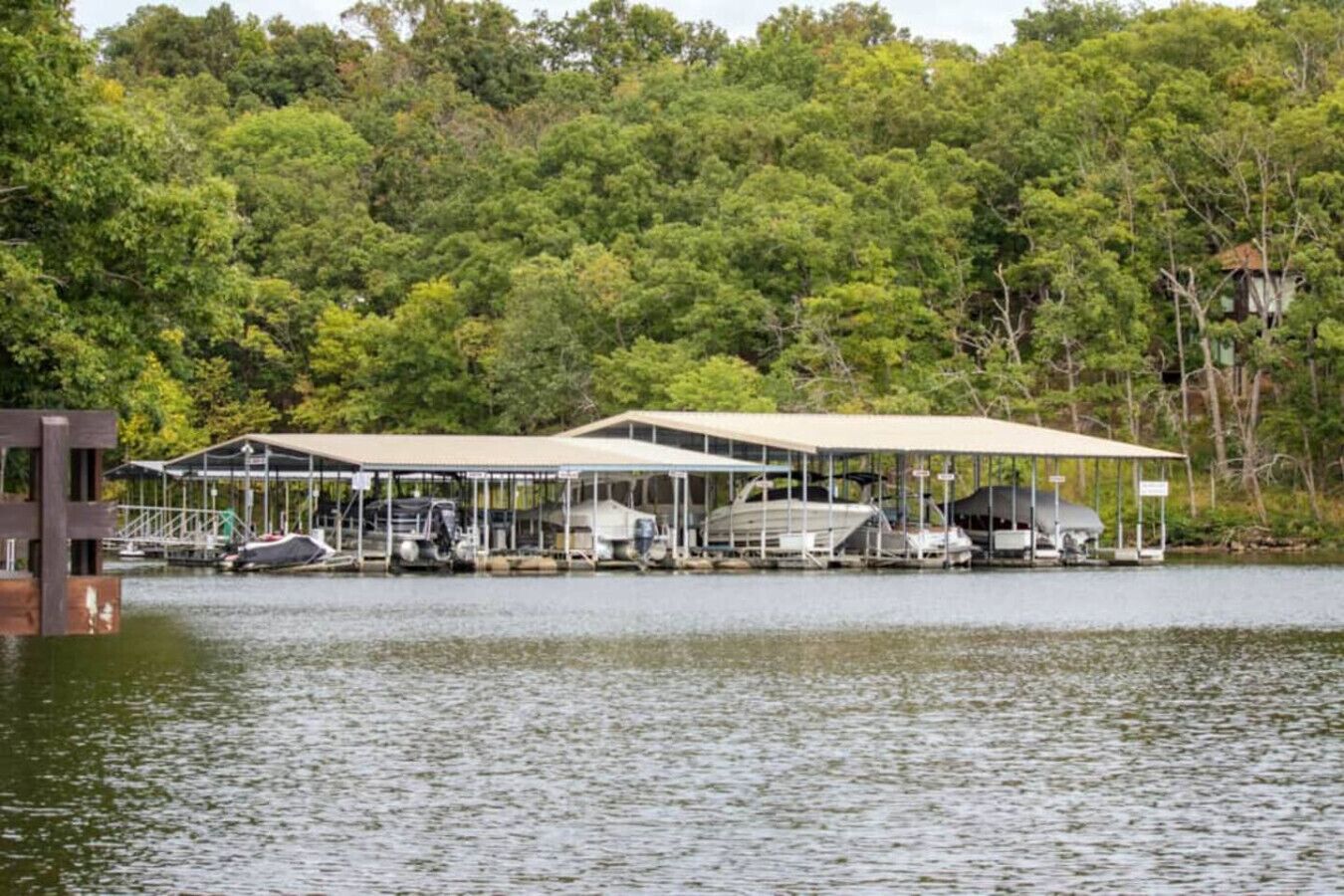 A lakeside dock with covered boat storage and a small building structure.