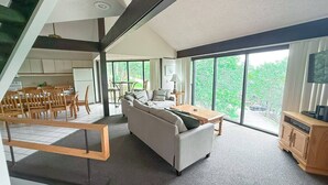 A modern living room with a sofa, coffee table, and dining area. - Treetop Village Treetop Escape #102-3BD/3BA/Pools/Grill/Dock/Deck-6PP (Village of Four Seasons)