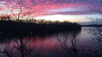 Ein friedlicher See mit Sonnenuntergangshimmel, dessen Spiegelung sich im Wasser zeigt, umgeben von Bäumen.