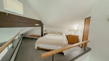 Une chambre à coucher avec un lit, une table de chevet, une lampe et une fenêtre avec des stores.