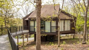 A cabin with a balcony, surrounded by trees and a wooden deck. - Treetop Village Willow Waters Escape#110-3BD/3BA/Pools/Deck/Dock/Grill-6PP (Village of Four Seasons)