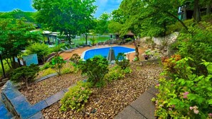 A swimming pool surrounded by lush greenery and a stone pathway. - Treetop Village Willow Waters Escape#110-3BD/3BA/Pools/Deck/Dock/Grill-6PP (Village of Four Seasons)