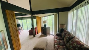 A spacious living room with a large window, a sofa, a coffee table, and a lamp.