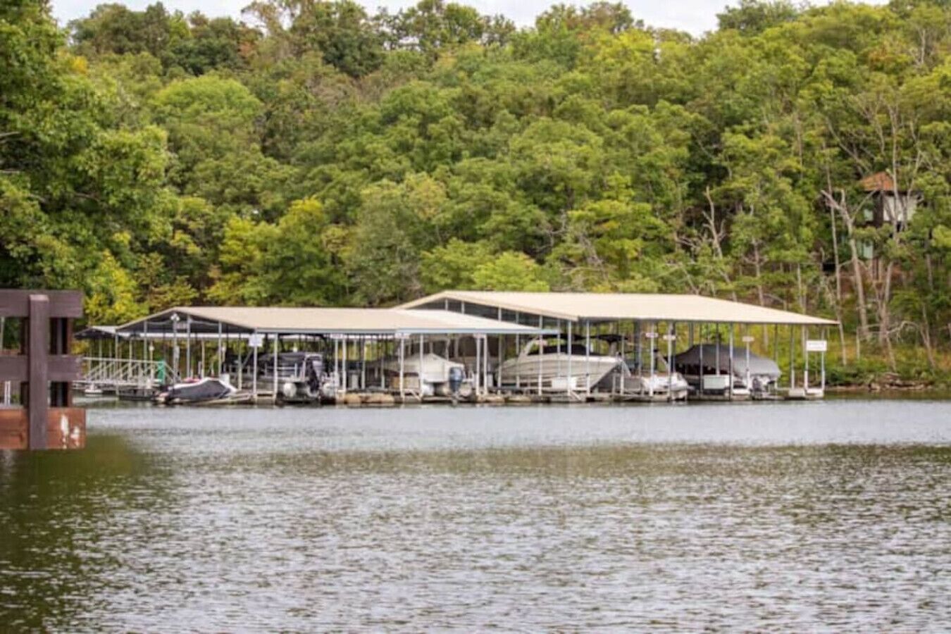Un muelle a orillas del lago con espacio cubierto para barcos y un edificio con terraza techada.
