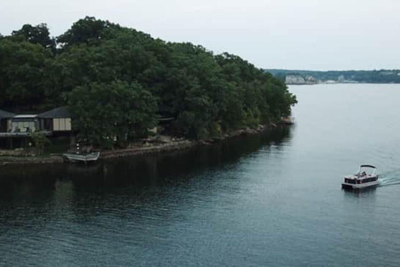A houseboat docked near a forested island with calm water.