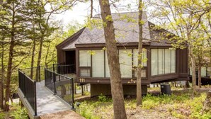 A cabin with a deck and a staircase leading to the entrance.