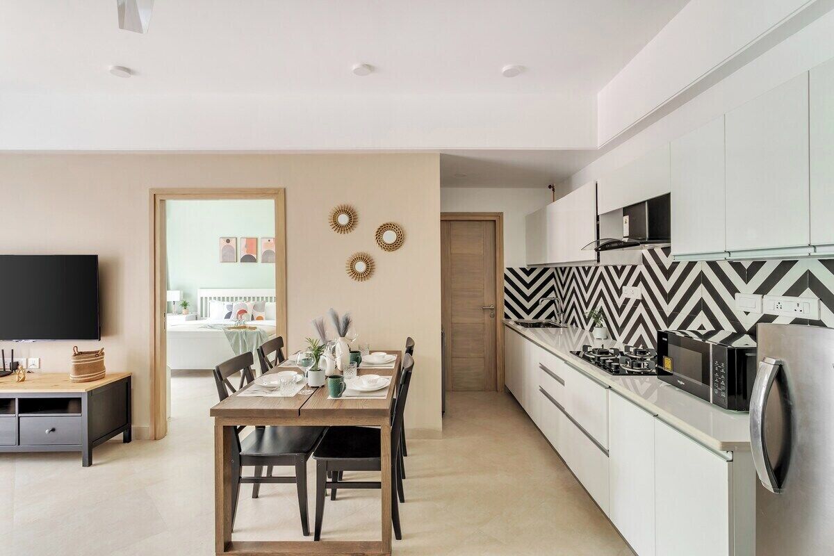 Una cocina moderna con armarios blancos, un salpicadero blanco y negro tipo espiga, y un refrigerador de acero inoxidable.