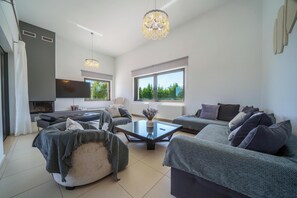 A modern living room with a glass coffee table, grey sofas, and a fireplace.