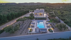 A modern villa with a swimming pool, surrounded by a landscaped garden and a view of the countryside. - Nostra Terra Villa, 2-acre Secluded Nature Escape (Perama Rethymno)