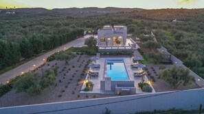 A modern villa with a swimming pool, surrounded by a landscaped garden and a view of the countryside.