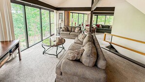 A spacious living room with a large sectional sofa, a coffee table, and a TV stand.