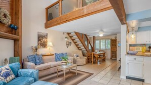 A spacious living area with a high ceiling, a dining area, and a kitchen.