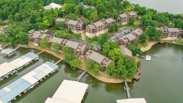 An aerial view of a residential area with multiple buildings, a dock, and a body of water.