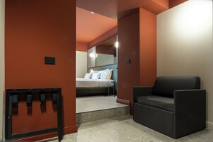 Una habitación de hotel moderna con una cama, un sofá negro y una mesita.