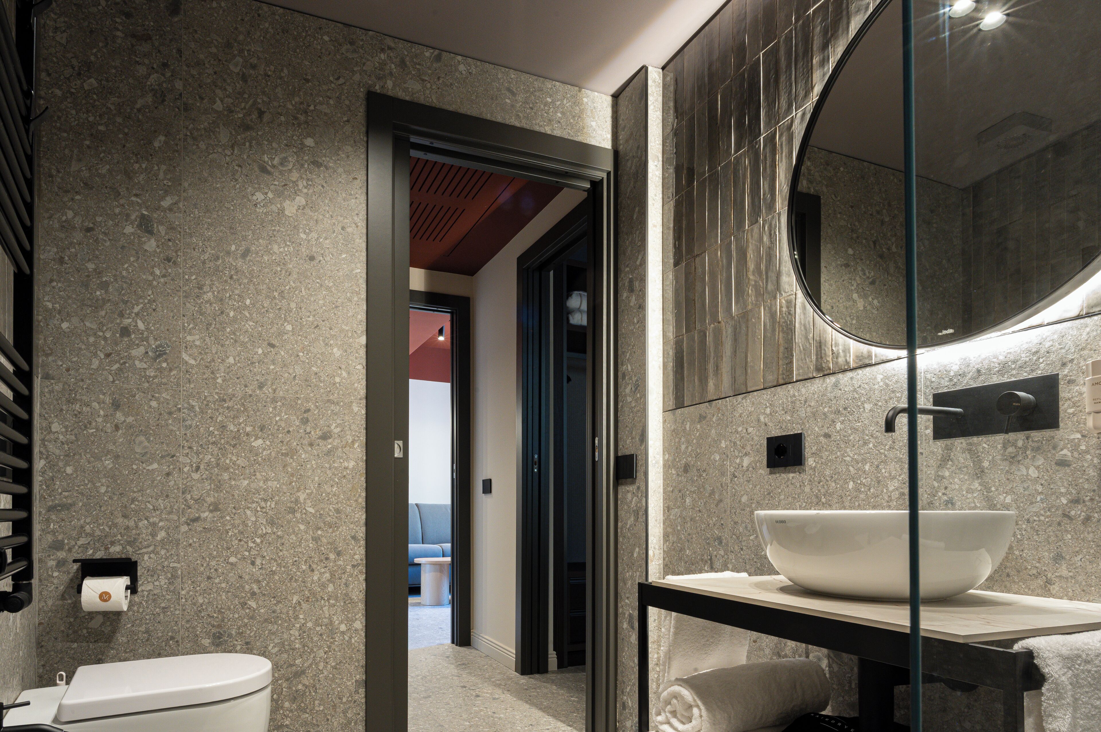 A modern bathroom with a large mirror, a white sink, and a toilet.