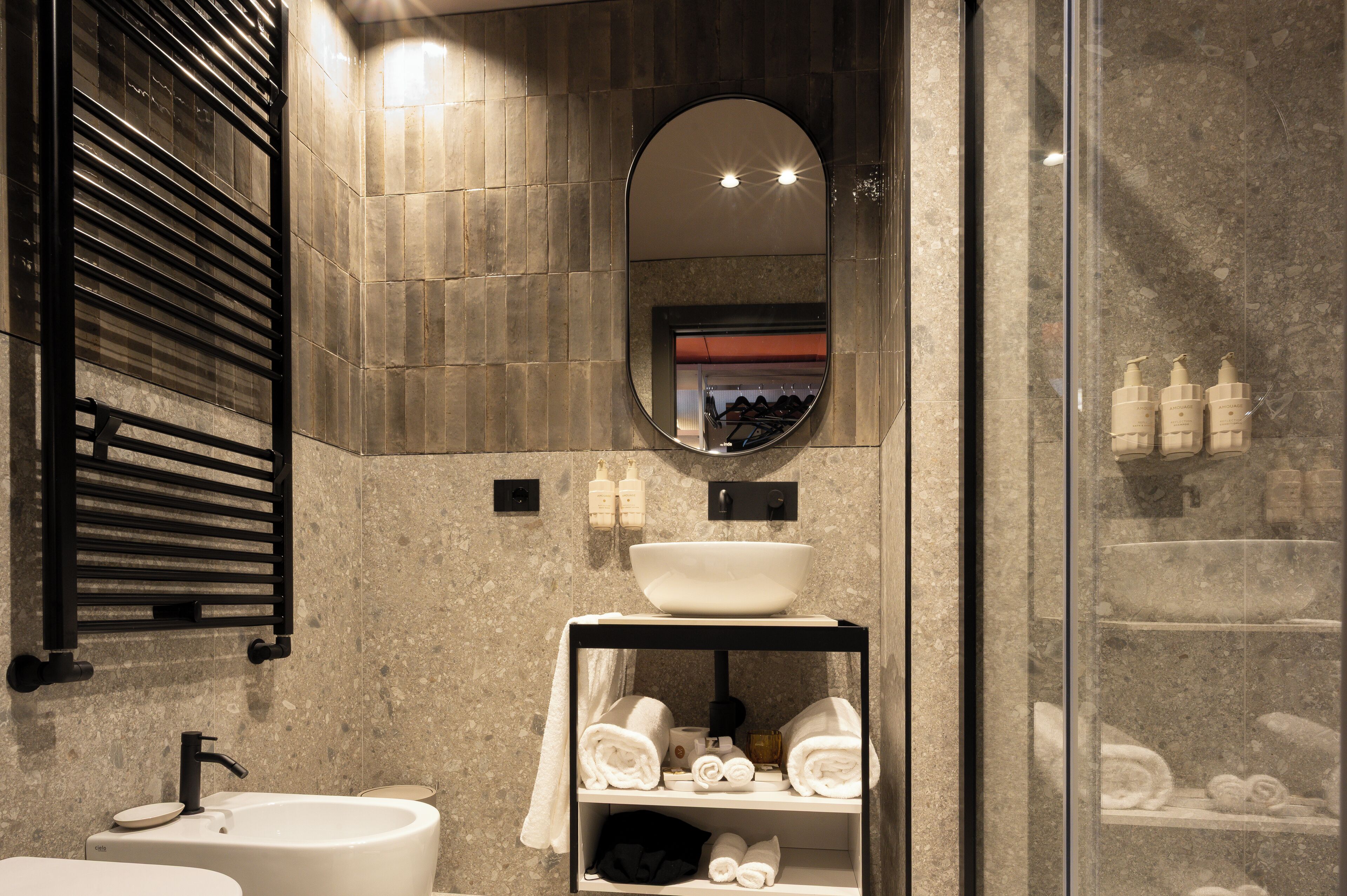Un baño moderno con un lavamanos independiente, un espejo y un estante con artículos de aseo.