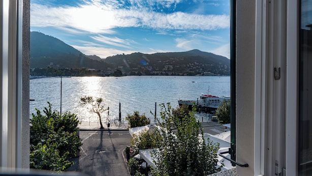 Vista de un lago con un muelle para botes, una montaña al fondo y un sendero que lleva al agua.