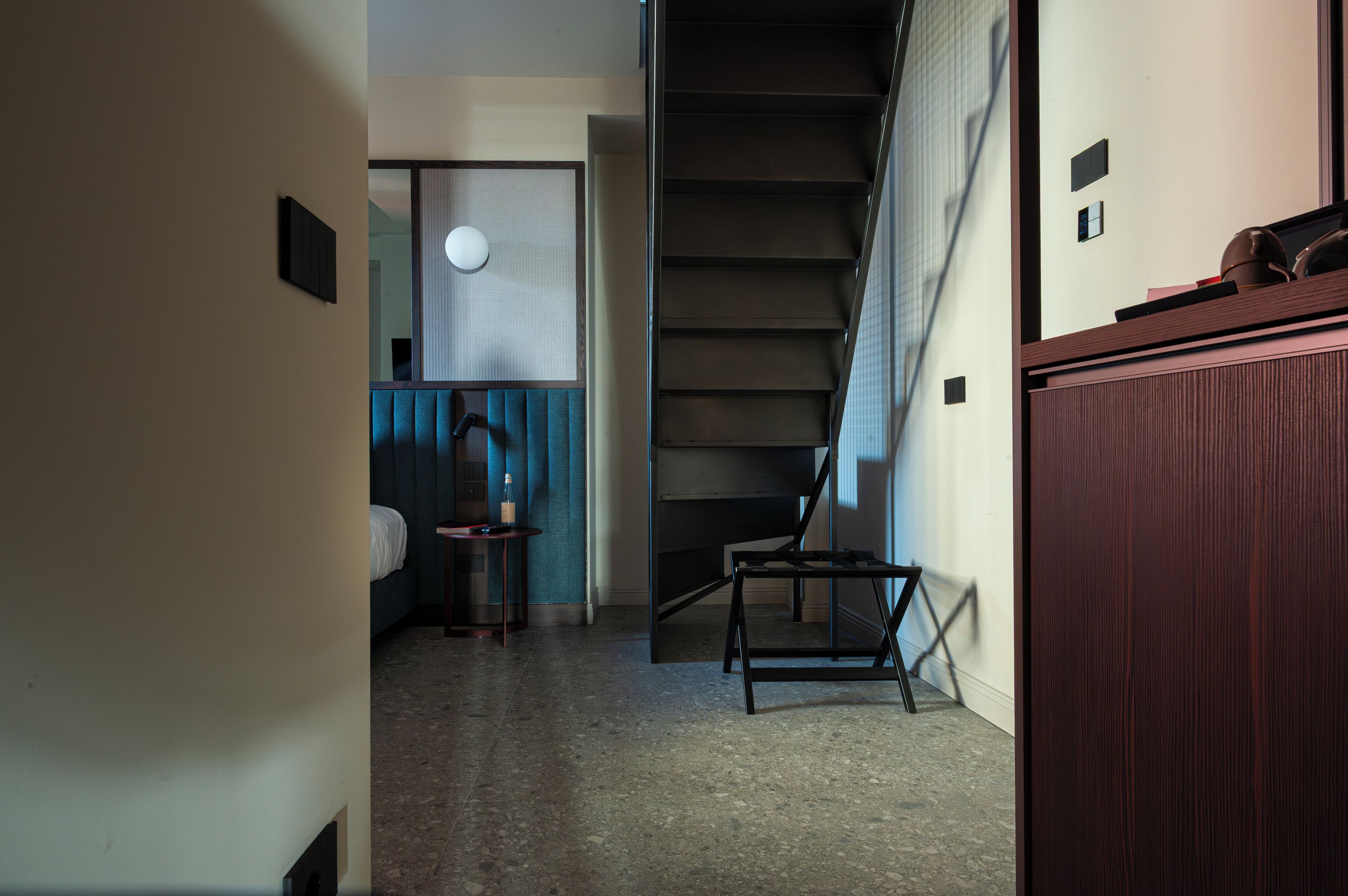 Ein Flur mit Treppe, einem Bett, einem kleinen Tisch und einem Schrank.