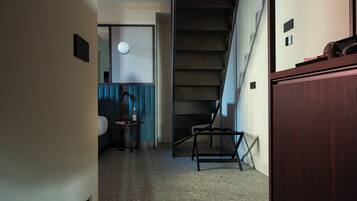Ein Flur mit Treppe, einem Bett, einem kleinen Tisch und einem Schrank.