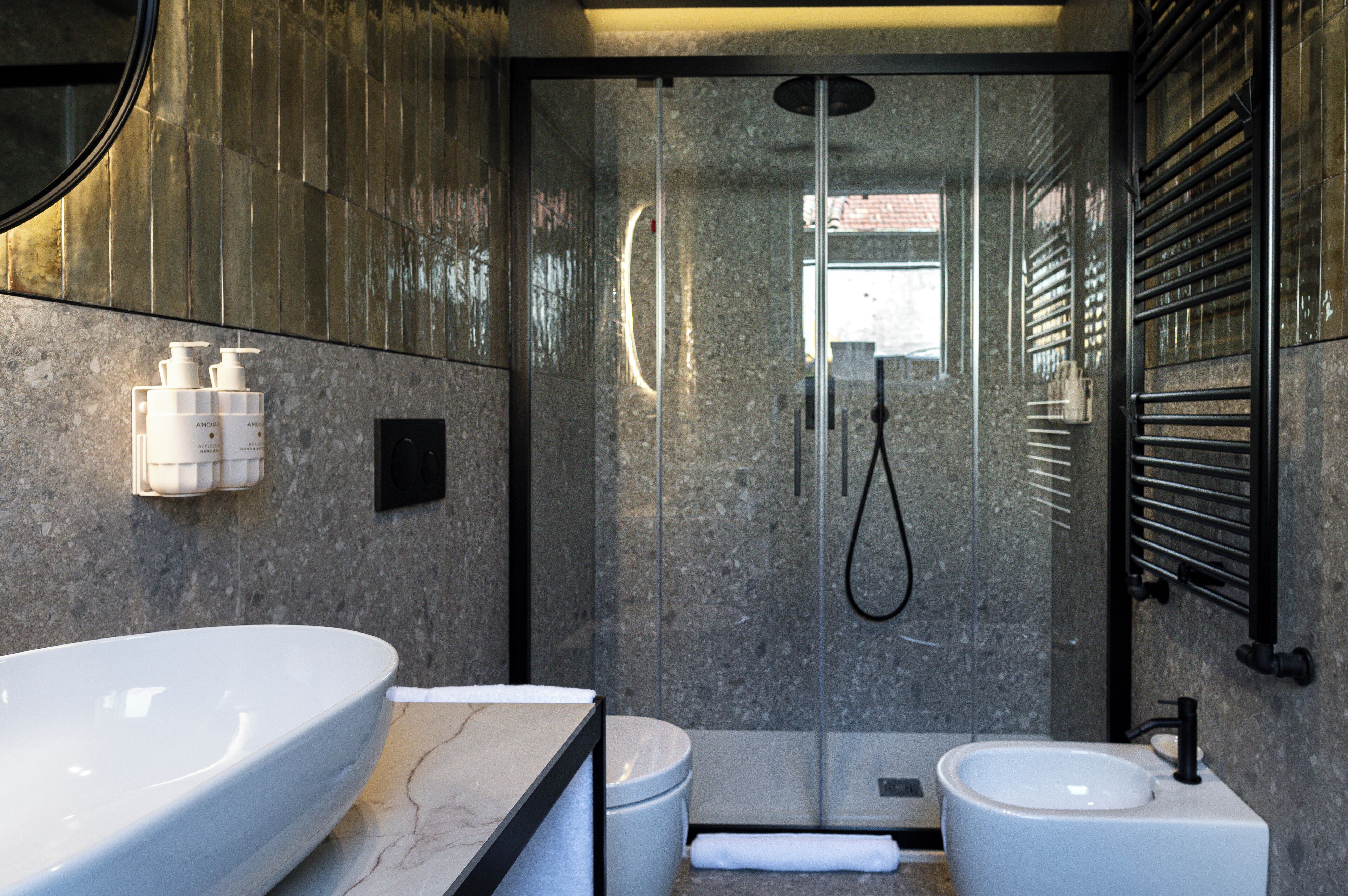 A modern bathroom with a large white sink, a smaller sink, and a glass-enclosed shower.