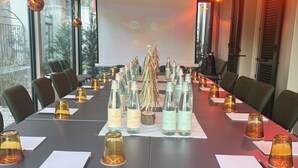 Un salón de conferencias con una larga mesa, sillas y una pantalla para proyector.