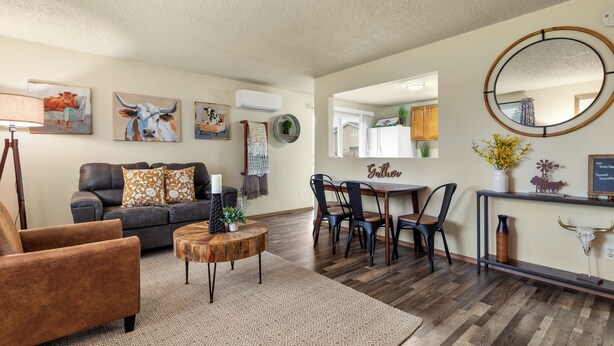 A living room with a brown leather sofa, a wooden coffee table, and a dining area with a table and chairs.