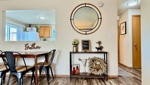 A dining area with a wooden table and chairs, a mirror on the wall, and a console table with decorative items.