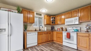 A kitchen with wooden cabinets, a white refrigerator, a microwave, a stove, and a dishwasher.