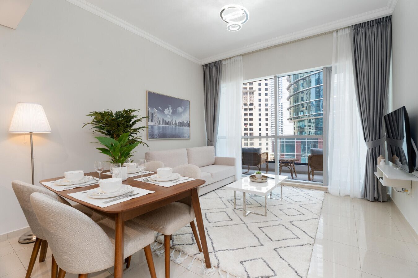 A modern living room with a dining area, a sofa, a coffee table, a TV, and a balcony with a city view.