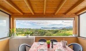 Un coin repas avec une table dressée pour deux personnes, offrant une vue panoramique sur un paysage magnifique, avec des montagnes et une végétation luxuriante.