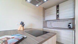 A modern kitchen with a built-in stove, a sink, and a countertop. There is a set of knives on a wooden block and a tablet on the counter. - SMERALDA Blue Sky (Portisco)