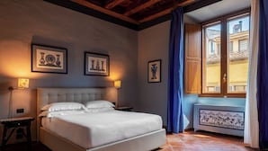 A bedroom with a bed, two bedside tables, a window with curtains, and framed artwork on the wall. - Antica Dimora De Benci (Florence)