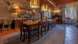 A dining area with a wooden table set for six, surrounded by chairs, with hanging light fixtures and wall-mounted plates. - Antica Dimora De Benci (Florence)