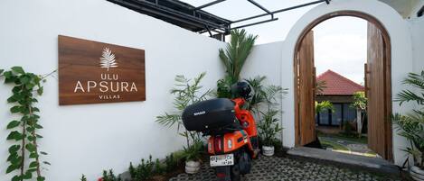 A scooter parked in front of a villa with a sign reading 'ULU Apsura Villas.'