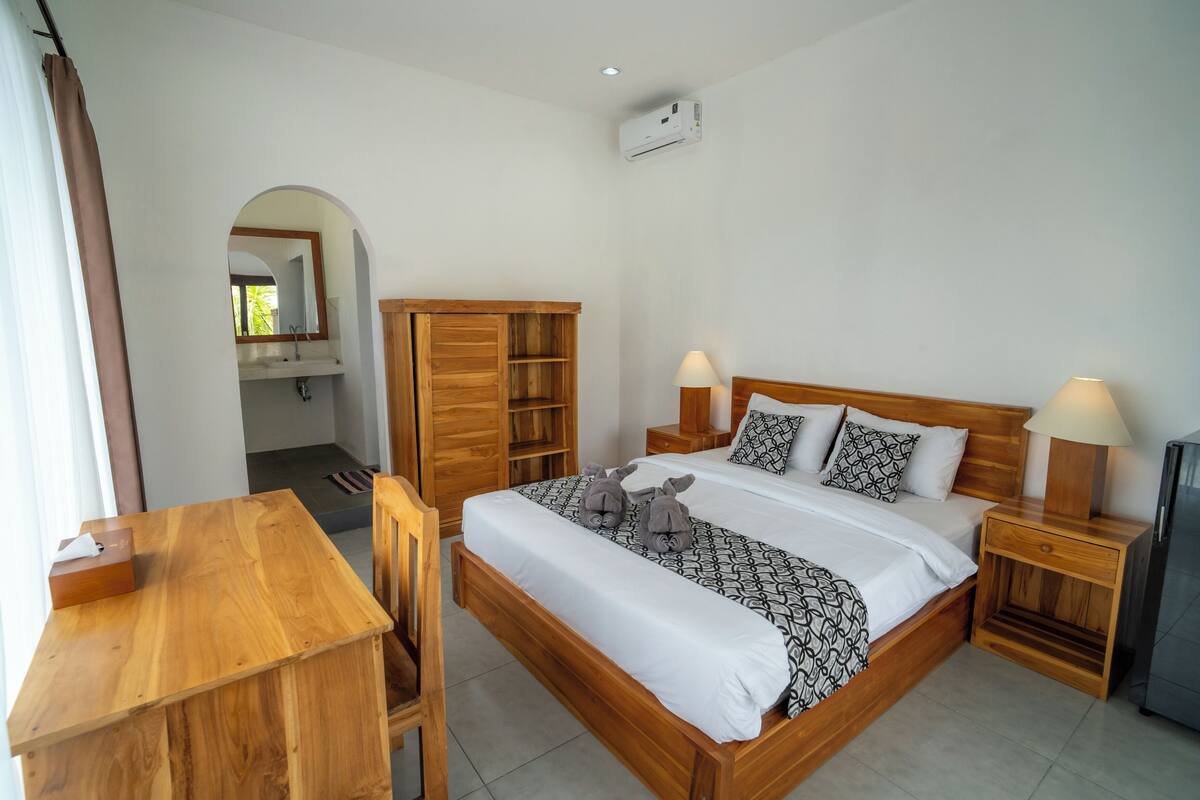 A bedroom with a wooden bed, bedside tables, a desk, and a wardrobe.