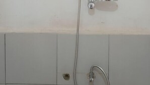 A shower with a handheld hose and a wall-mounted showerhead.