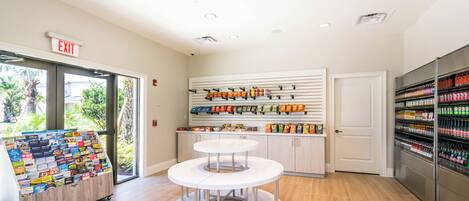 A clean, well-lit store with an exit sign, a display of snacks, and a refrigerated section.