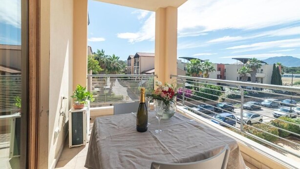 A balcony with a table, a bottle of champagne, and a vase of flowers.