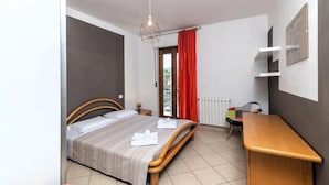 A bedroom with a bed, bedside table, and a hanging light fixture.