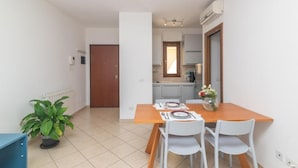 A compact kitchen with a dining area, a potted plant, and a view of the living room.