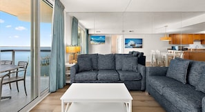 A modern living room with a sofa, a coffee table, and a dining area with chairs.