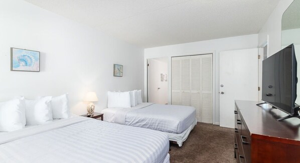 A hotel room with two beds, a desk, a television, and a wardrobe.