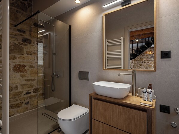 A modern bathroom with a glass-enclosed shower, a white sink, and a wooden vanity.