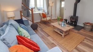 A cozy living room with a sofa, a wooden coffee table, and a fireplace. - Puffin Cottage (Alnwick)