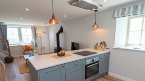 A modern kitchen with a central island, built-in oven, and pendant lighting. - Puffin Cottage (Alnwick)