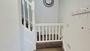 A staircase with a white railing, a white door with a small shelf, and a wall-mounted light fixture. - 2 Bed Cottage-sleeps 4-private Garden-parking (Omagh)