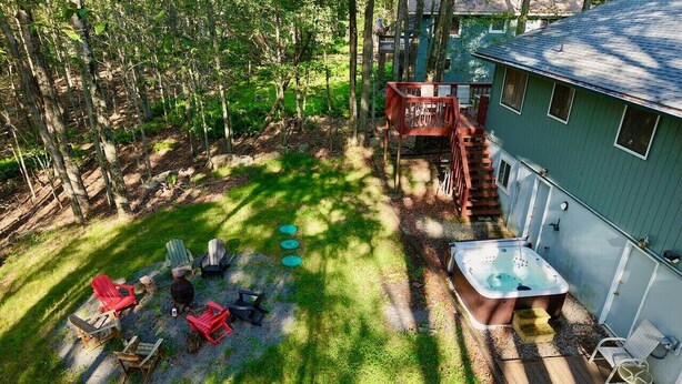 A backyard with a hot tub, deck chairs, and a wooden table. - Throwback Lodge - Hot Tub - Pet Friendly (Gouldsboro)
